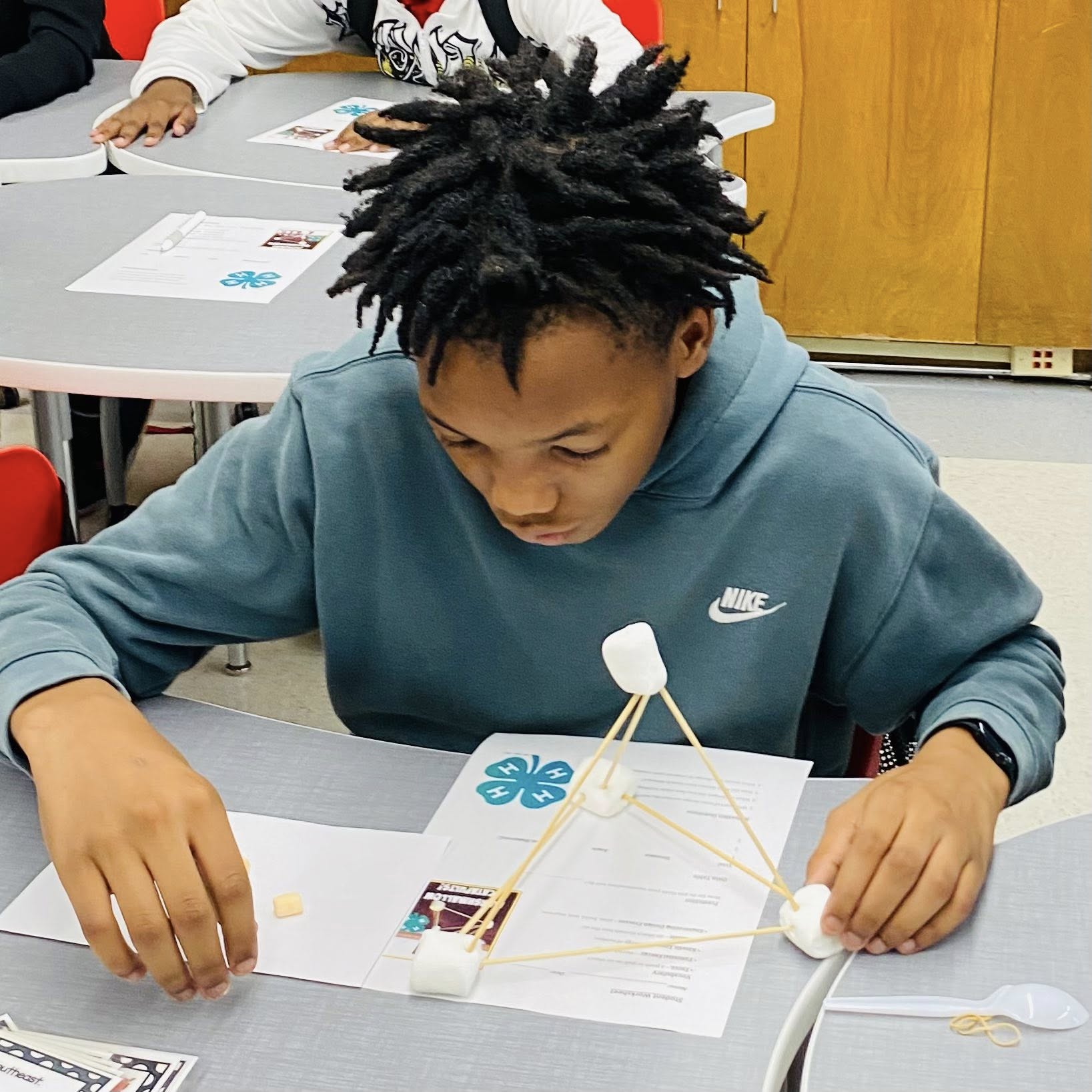 A boy reading a paper at his desk.